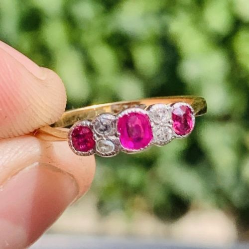 fig 1. An 18ct yellow gold ring featuring three oval pinkish-red rubies interspersed with pairs of small round old-cut diamonds in a platinum setting.