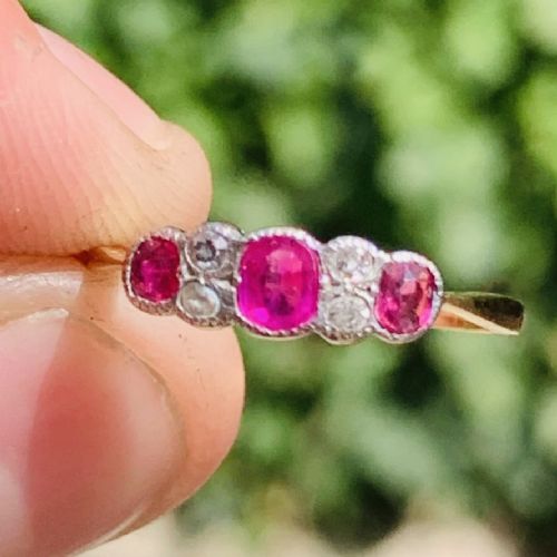 An 18ct yellow gold ring featuring three oval pinkish-red rubies interspersed with pairs of small round old-cut diamonds in a platinum setting. View III