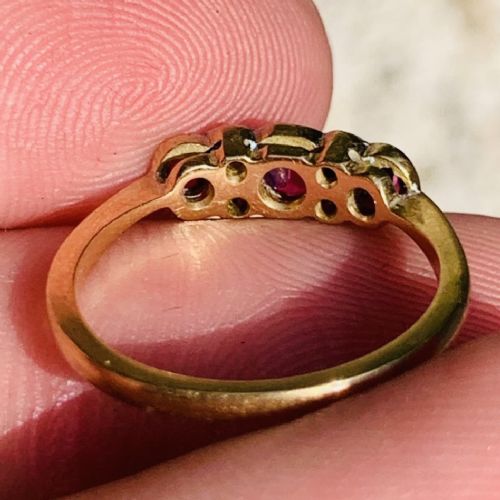 An 18ct yellow gold ring featuring three oval pinkish-red rubies interspersed with pairs of small round old-cut diamonds in a platinum setting. View V