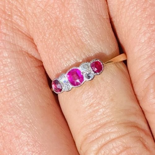An 18ct yellow gold ring featuring three oval pinkish-red rubies interspersed with pairs of small round old-cut diamonds in a platinum setting. View VIII