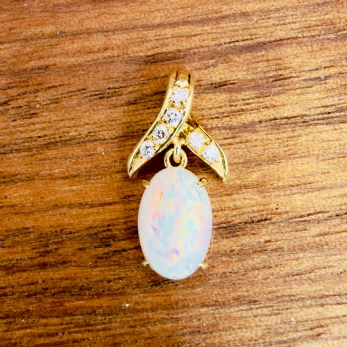 fig 1. A 14ct yellow gold pendant featuring a claw-set cabochon opal hanging beneath a diamond-accented bail.