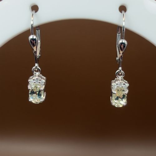 fig 1. A pair of 9ct white gold drop earrings featuring oval cut pale green amethysts suspended beneath small diamond cluster accents with hinge back fastenings.