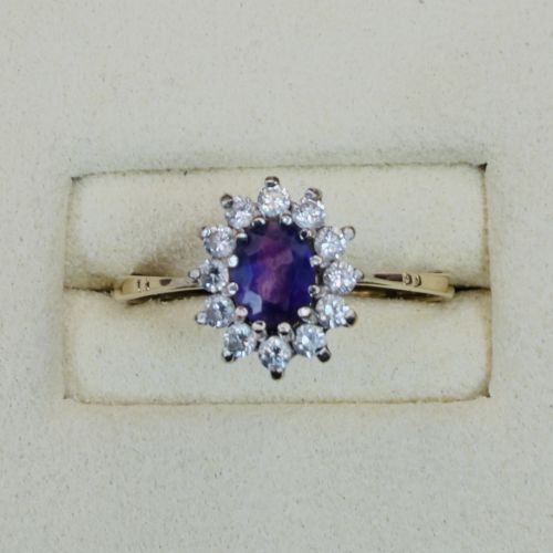 fig 1. A vintage 9ct yellow gold ring featuring a central oval purple amethyst framed by a halo cluster of round white spinel gemstones.