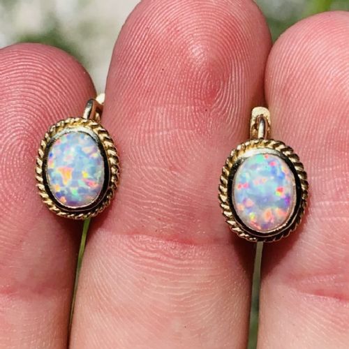 A pair of 14ct yellow gold stud earrings featuring oval cabochon opals surrounded by a textured rope-twist border.
