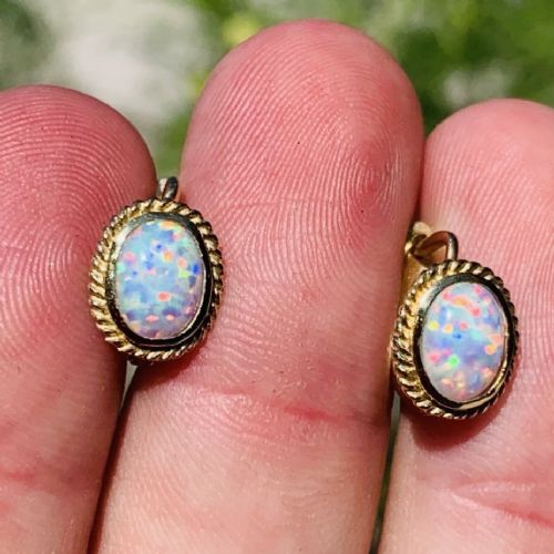 A pair of 14ct yellow gold stud earrings featuring oval cabochon opals surrounded by a textured rope-twist border. View II