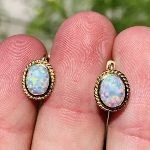 A pair of 14ct yellow gold stud earrings featuring oval cabochon opals surrounded by a textured rope-twist border. View III