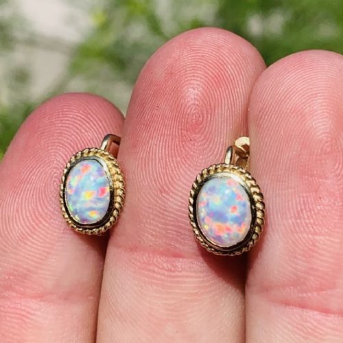 A pair of 14ct yellow gold stud earrings featuring oval cabochon opals surrounded by a textured rope-twist border. View IV