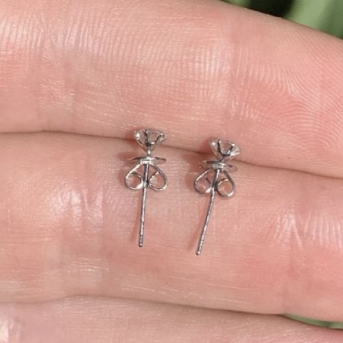 A pair of round brilliant-cut solitaire diamond stud earrings set in six-claw platinum mounts. View VI