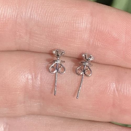 A pair of round brilliant-cut solitaire diamond stud earrings set in six-claw platinum mounts. View VII