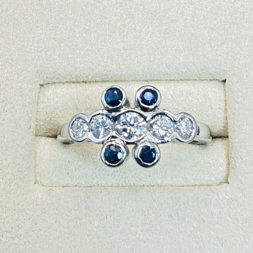 fig 1. A platinum ring crafted with five bezel-set diamonds in a central horizontal row, flanked by four small round blue sapphires.