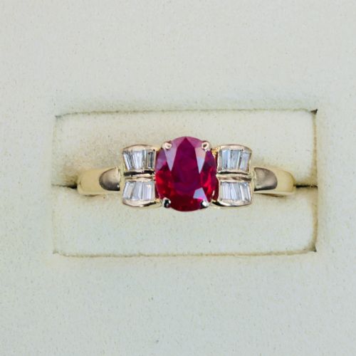 fig 1. An 18ct yellow gold ring featuring an oval cut central red ruby flanked by stepped baguette cut diamonds on a polished band.