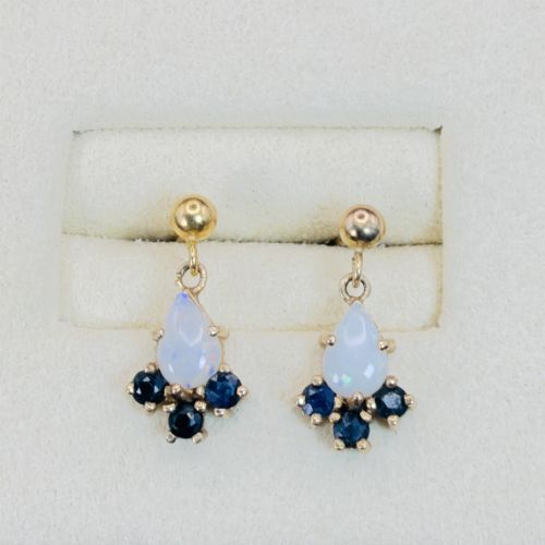 fig 1. A pair of 9ct yellow gold stud drop earrings featuring pear-shaped white opal cabochons accented with three round blue sapphires at the base.
