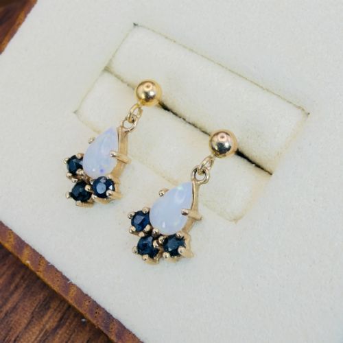 fig 2. A pair of 9ct yellow gold stud drop earrings featuring pear-shaped white opal cabochons accented with three round blue sapphires at the base.