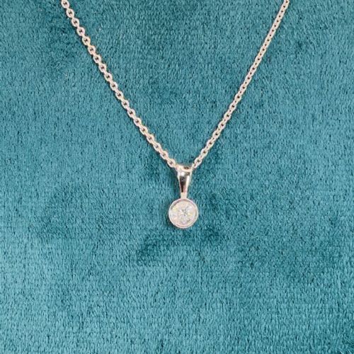 fig 1. A single round brilliant-cut diamond set in a white gold bezel pendant suspended from a fine white gold chain.