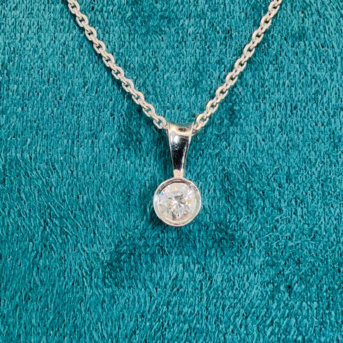 fig 2. A single round brilliant-cut diamond set in a white gold bezel pendant suspended from a fine white gold chain.