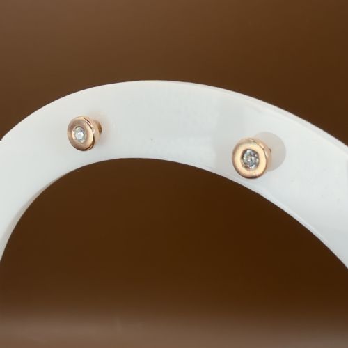 fig 2. A pair of circular 9ct rose gold stud earrings featuring round bezel-set natural diamonds.