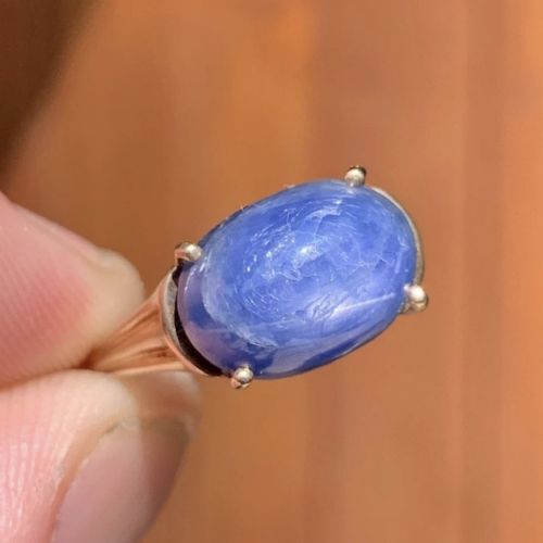 fig 1. A vintage 9ct yellow gold ring featuring a central oval cabochon blue sapphire set in four claws.