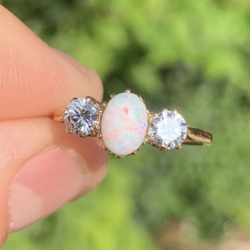 fig 1. An 18ct yellow gold Art Deco ring featuring an oval cabochon opal flanked by two round diamonds in claw settings.