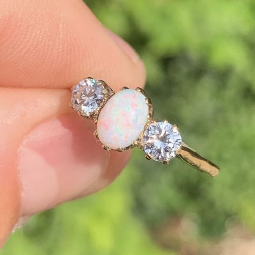 fig 2. An 18ct yellow gold Art Deco ring featuring an oval cabochon opal flanked by two round diamonds in claw settings.