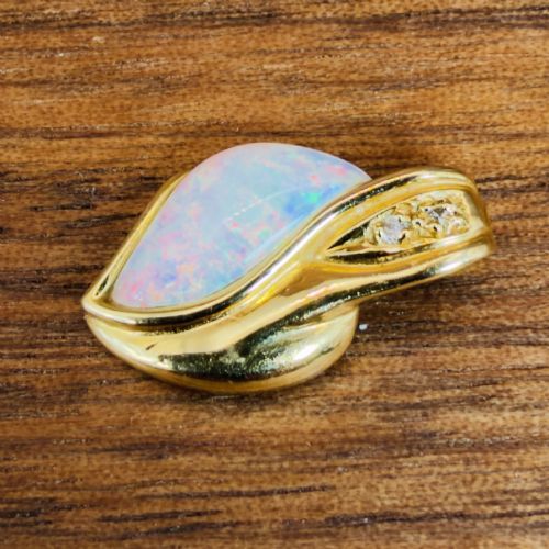 fig 2. An 18ct yellow gold freeform pendant displaying an iridescent white opal with green and pink flash, set alongside two accent diamonds on the bail.