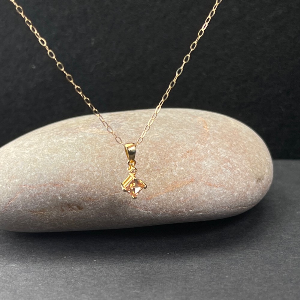 A 9ct gold necklace featuring a square cognac topaz pendant set diagonally, topped with a small accent diamond and attached to a fine gold trace chain. View III