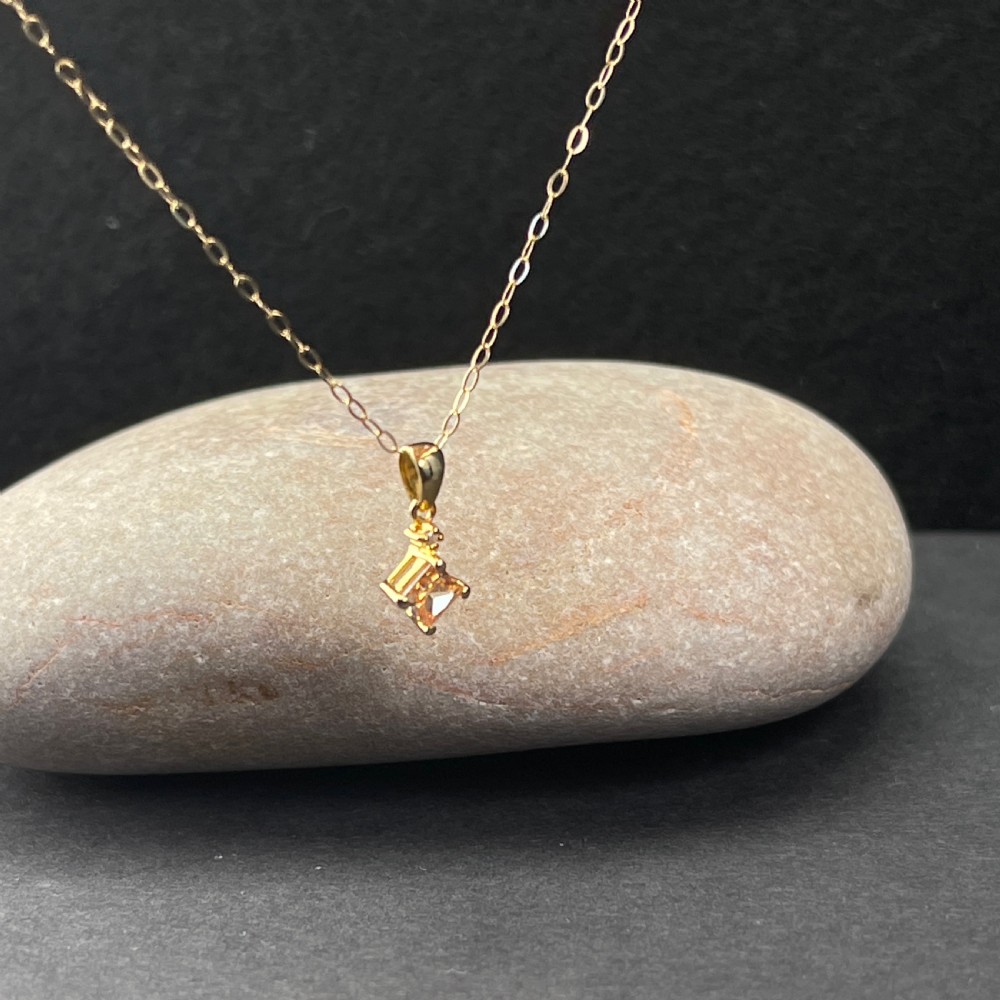 A 9ct gold necklace featuring a square cognac topaz pendant set diagonally, topped with a small accent diamond and attached to a fine gold trace chain. View IV