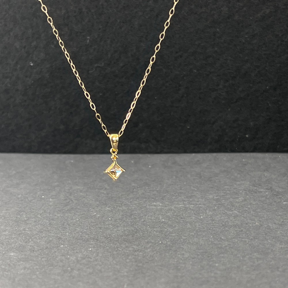 A 9ct gold necklace featuring a square cognac topaz pendant set diagonally, topped with a small accent diamond and attached to a fine gold trace chain. View V