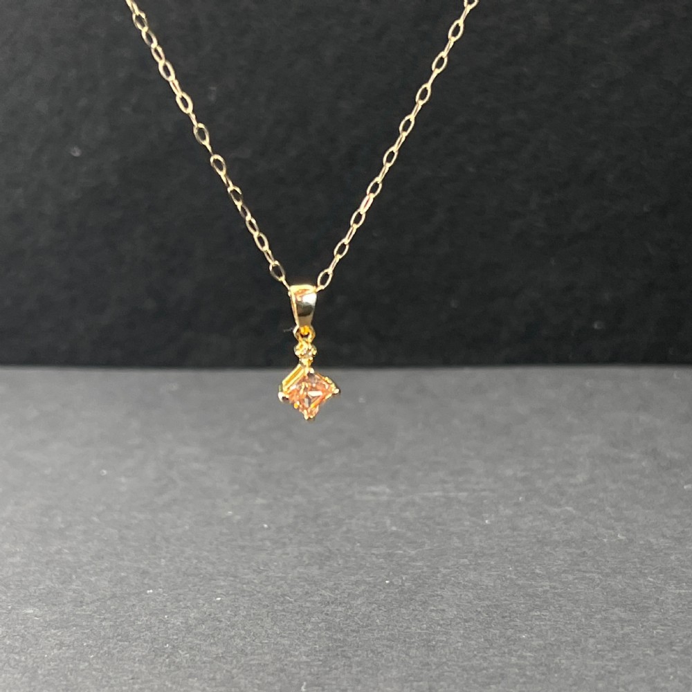 A 9ct gold necklace featuring a square cognac topaz pendant set diagonally, topped with a small accent diamond and attached to a fine gold trace chain. View VI
