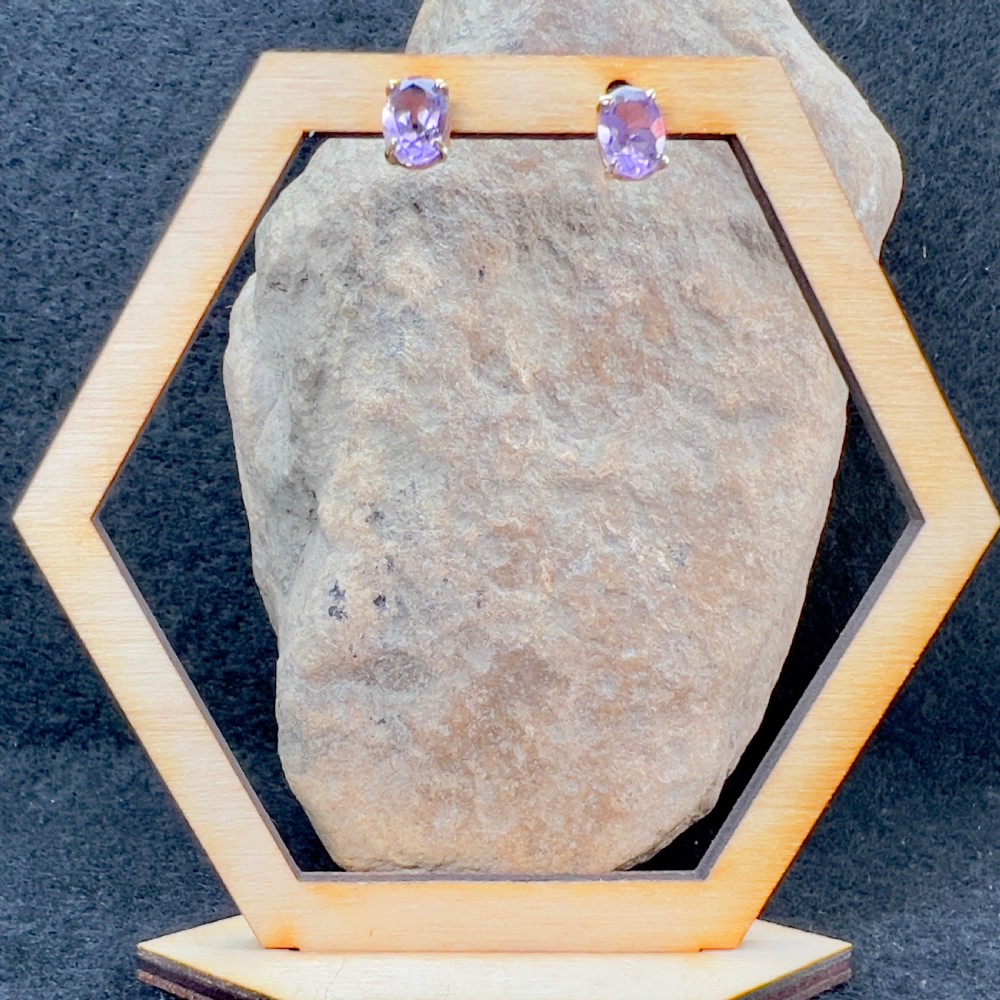 A pair of 9ct yellow gold stud earrings, each featuring an oval-cut purple amethyst gemstone in a four-claw setting. View V