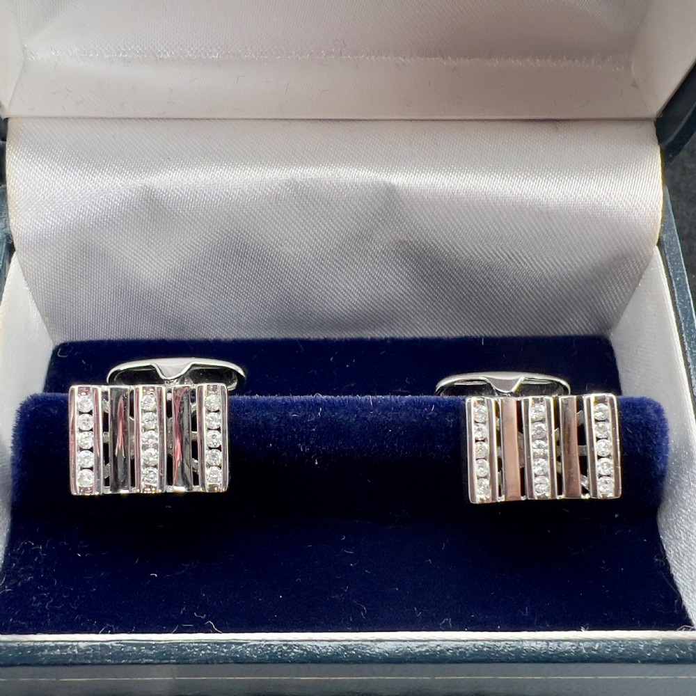 A pair of rectangular 9ct white gold cufflinks featuring alternating polished vertical bars and channel-set diamonds.