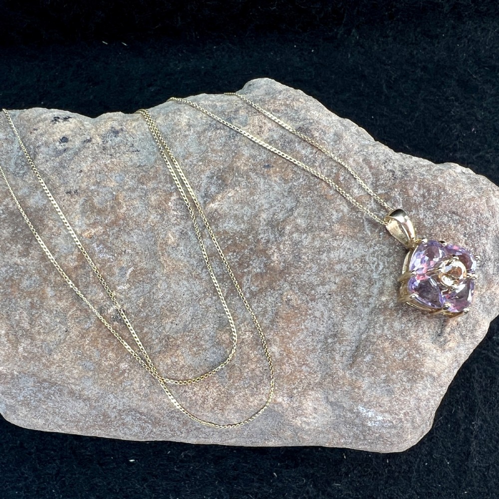 A 9ct yellow gold chain supporting a square purple amethyst pendant featuring a central cluster with a light citrine stone. View IX