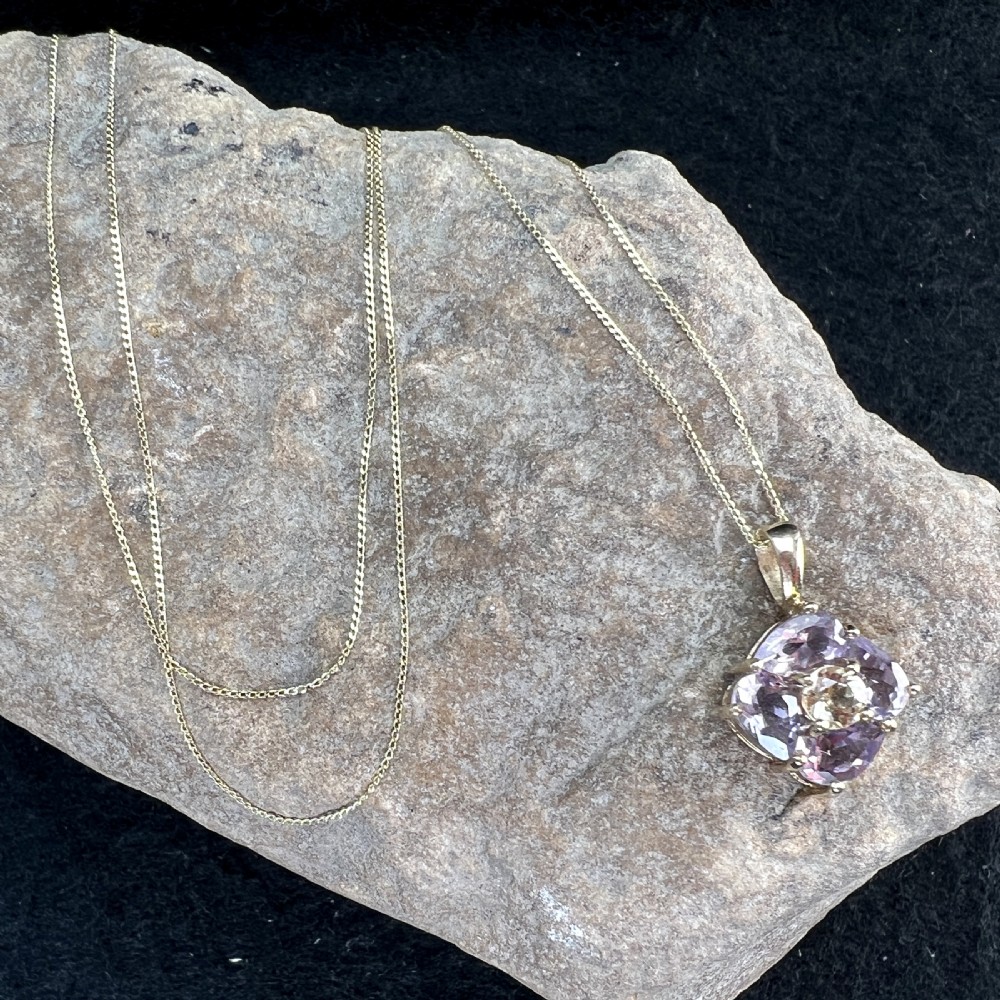 A 9ct yellow gold chain supporting a square purple amethyst pendant featuring a central cluster with a light citrine stone. View X