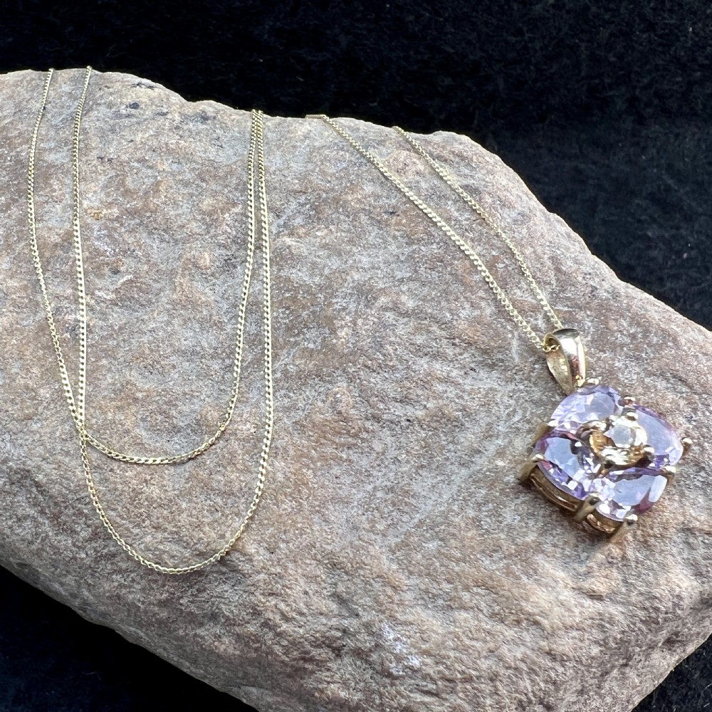 A 9ct yellow gold chain supporting a square purple amethyst pendant featuring a central cluster with a light citrine stone. View XI