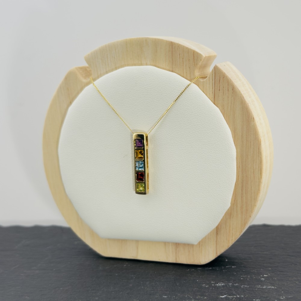 A 9ct yellow gold vertical bar pendant containing five square-cut multi-coloured gemstones suspended from a delicate gold chain. View X