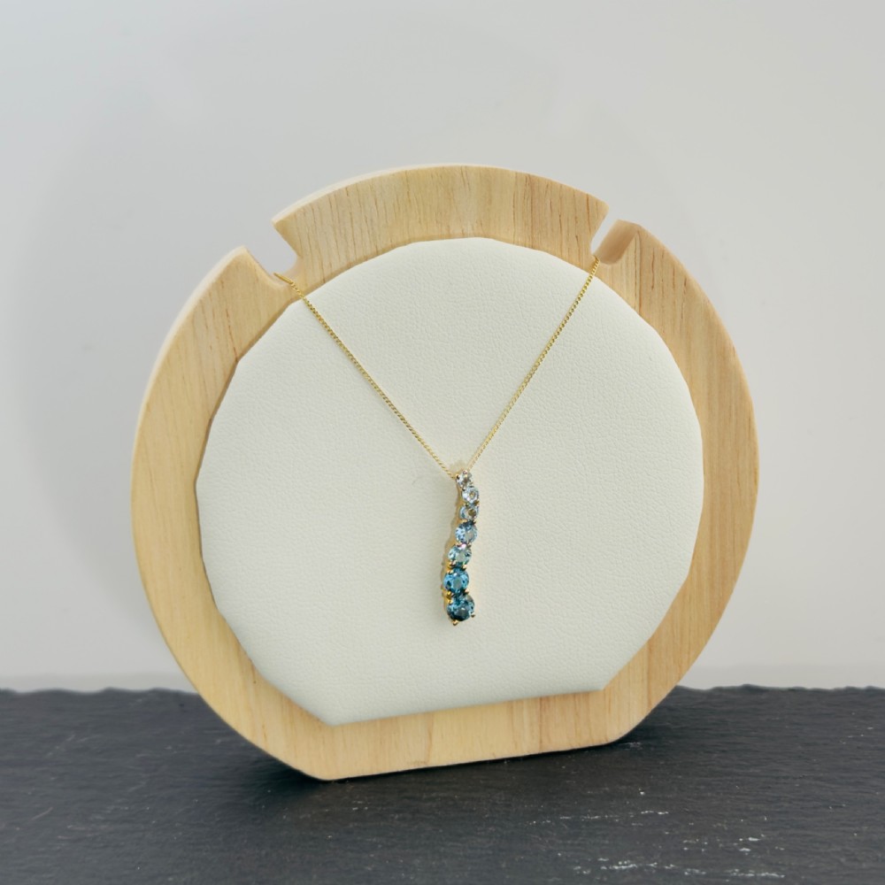 A 9ct yellow gold wave-shaped pendant featuring a vertical line of graduated blue topaz gemstones suspended from a fine chain. View II