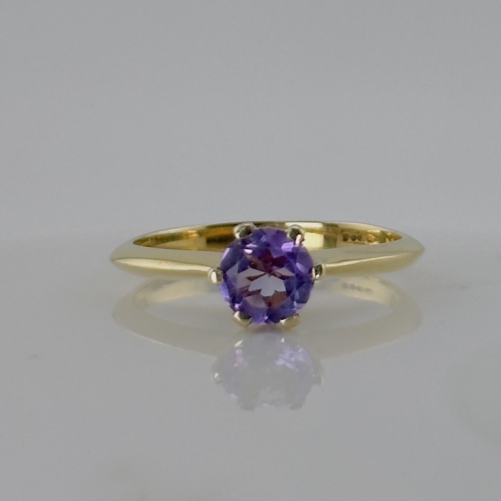 A vintage 9ct yellow gold ring featuring a single round faceted purple amethyst in a claw setting.