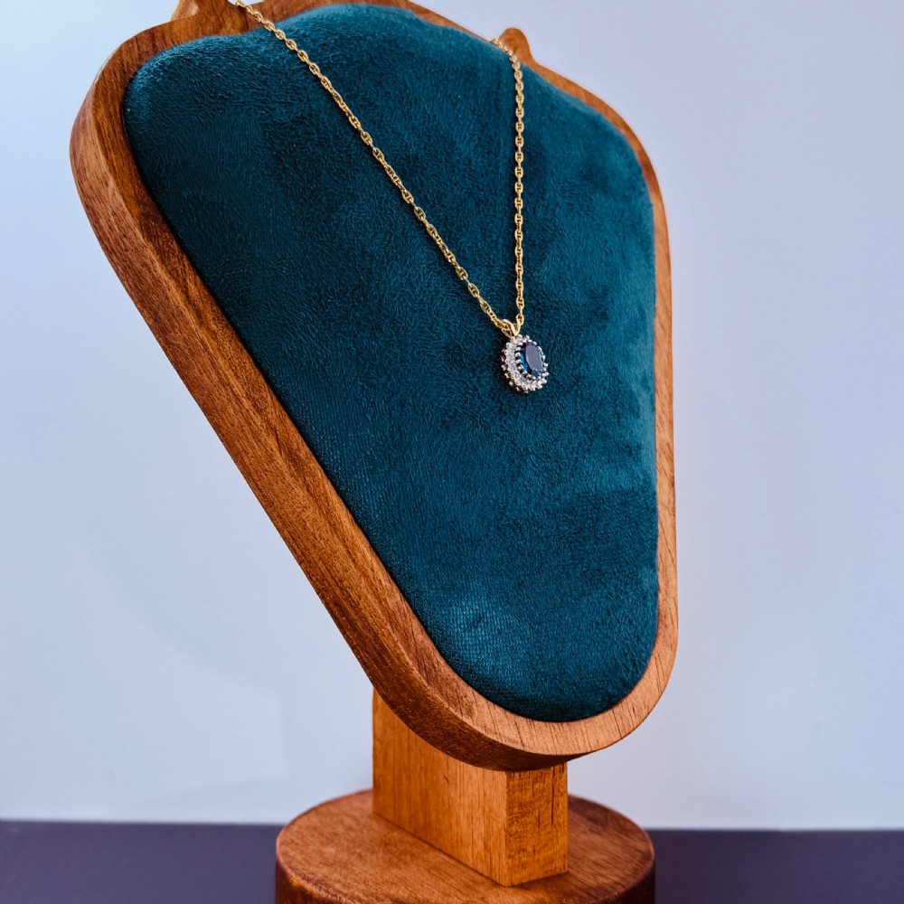 A 9ct yellow gold chain supporting an oval blue zircon pendant surrounded by a halo of small diamonds. View IV