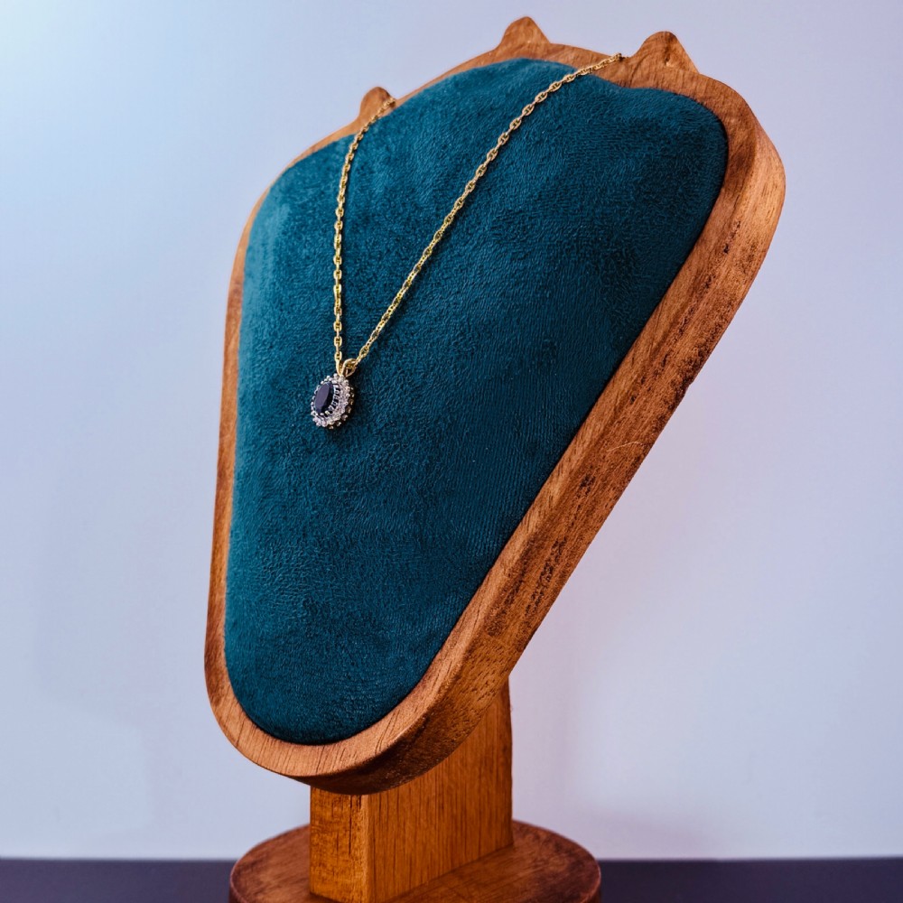 A 9ct yellow gold chain supporting an oval blue zircon pendant surrounded by a halo of small diamonds. View V