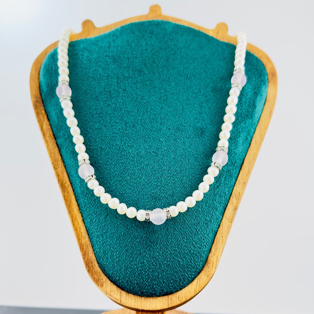 A single strand necklace composed of white cultured pearls interspersed with round pale pink rose quartz beads and silver-toned paste stone spacer rondelles.