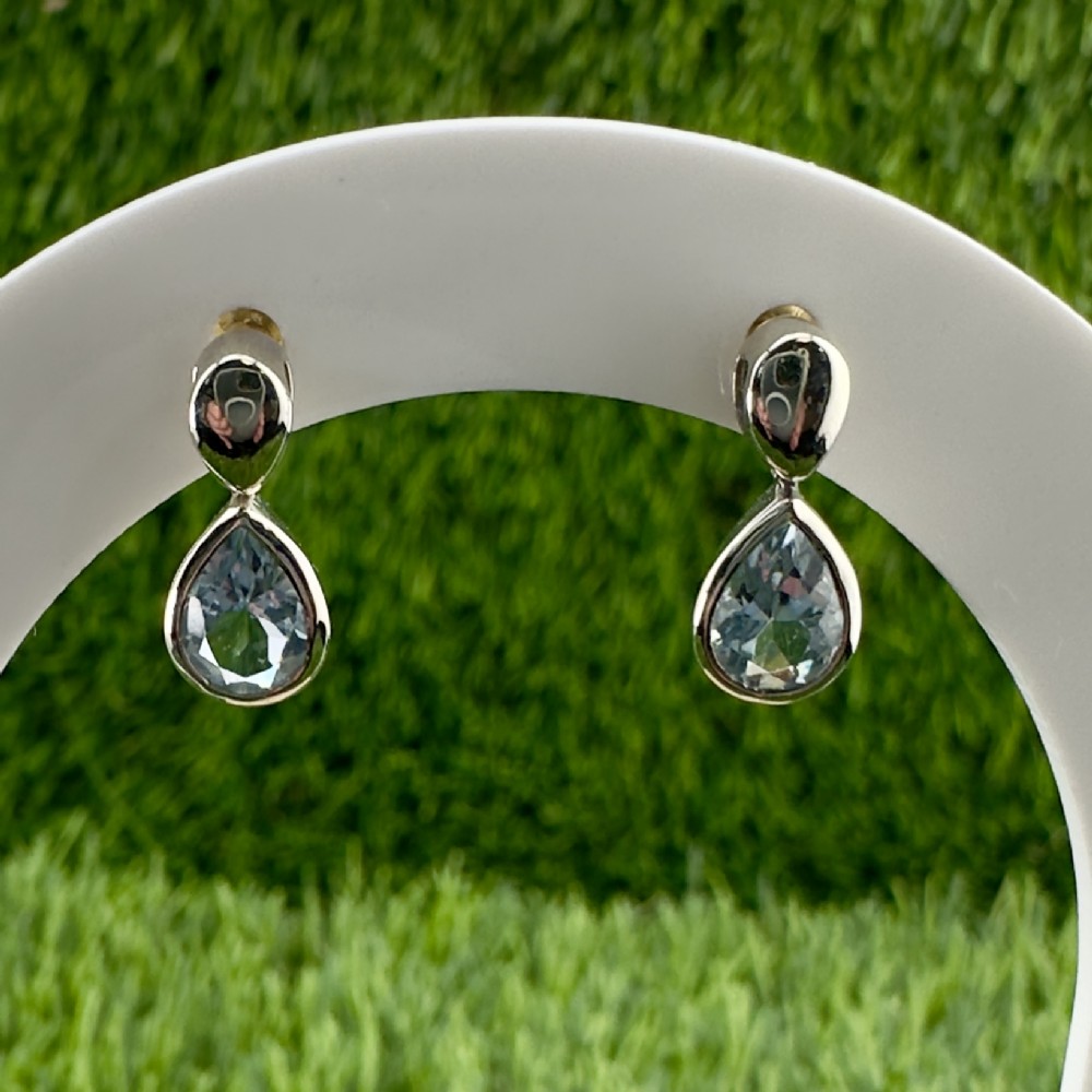 A pair of 9ct white gold drop stud earrings featuring bezel-set, pear-cut aquamarine gemstones.