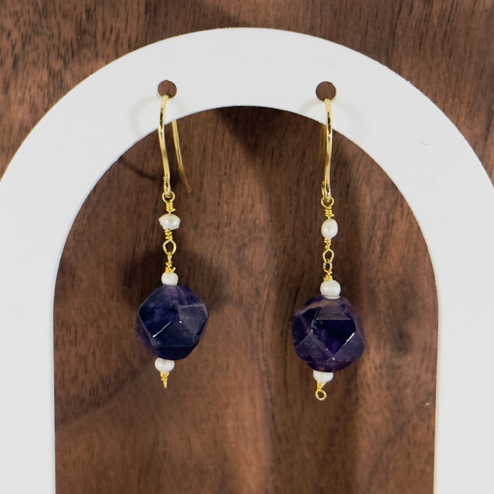 A pair of 9ct yellow gold drop earrings featuring geometric faceted purple amethyst beads accented with small white seed pearls.