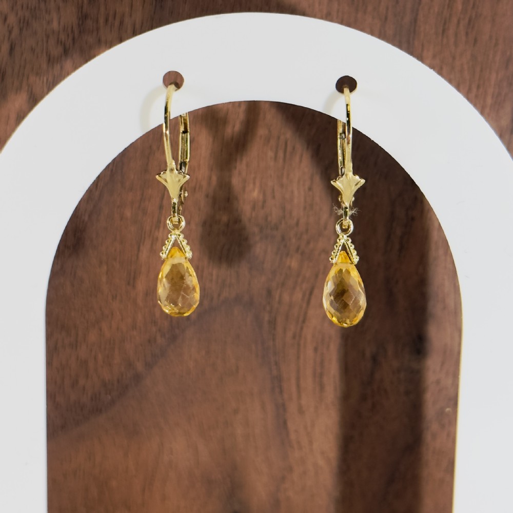 A pair of 9ct yellow gold drop earrings featuring teardrop-shaped faceted citrine gemstones suspended from decorative hinged lever back fastenings.