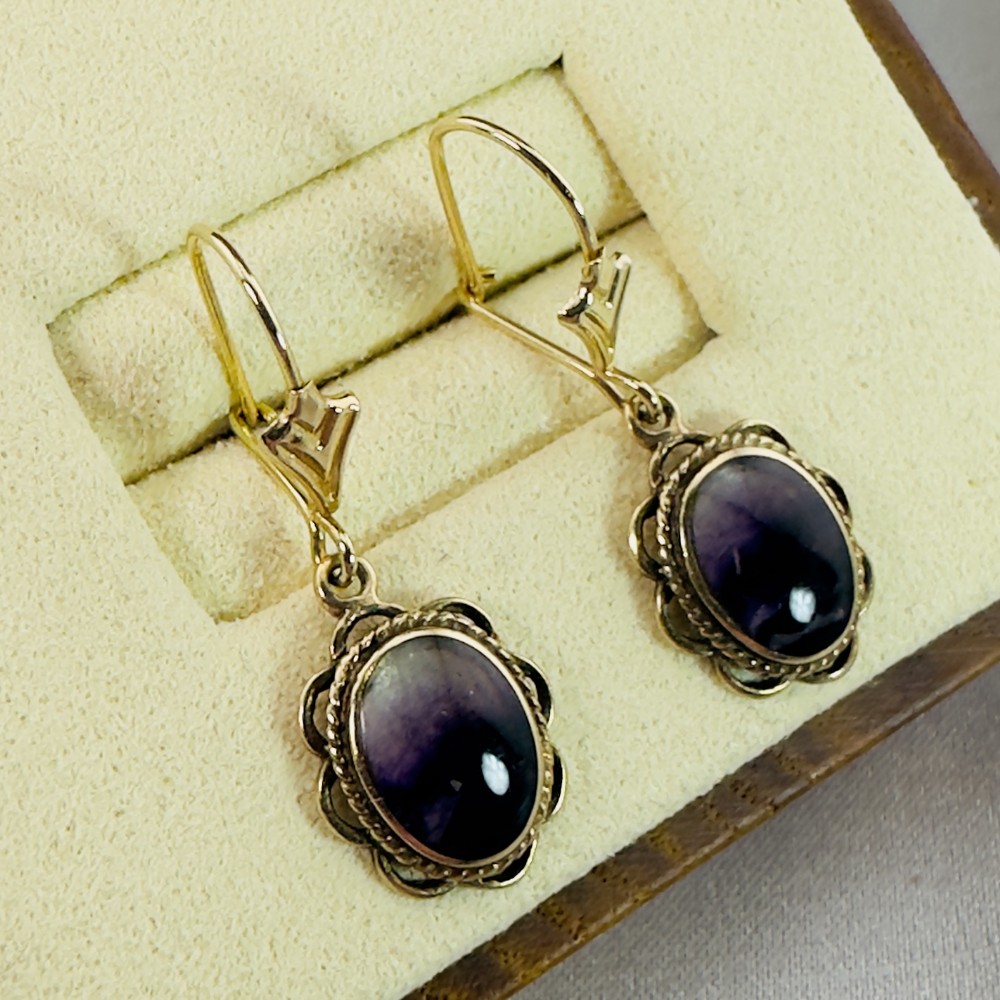 A pair of 9ct yellow gold drop earrings featuring oval purple Blue John cabochons set within decorative rope-twist frames.