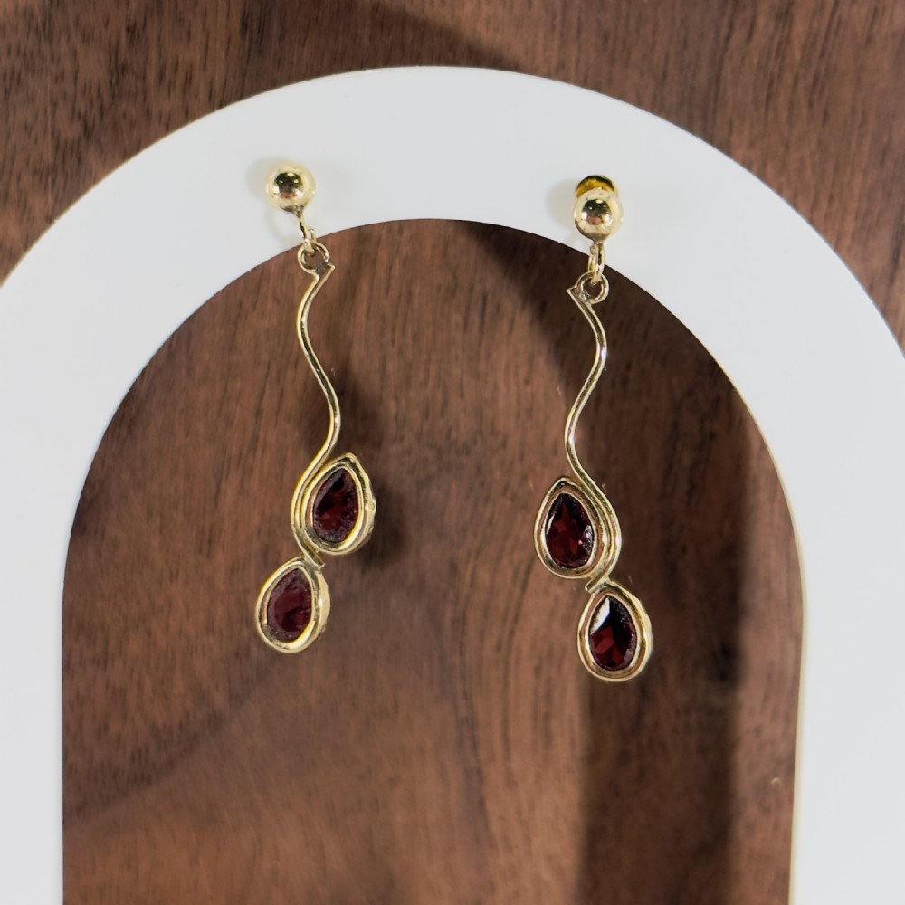 Pair of 9ct yellow gold drop earrings with ball studs, wavy wire drops, and two bezel-set teardrop garnets.