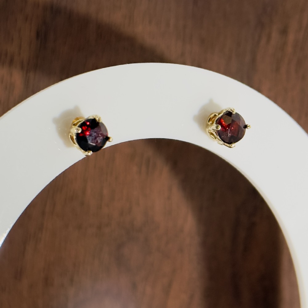A pair of round cut deep red garnet stud earrings set in four-claw 14ct yellow gold mountings.