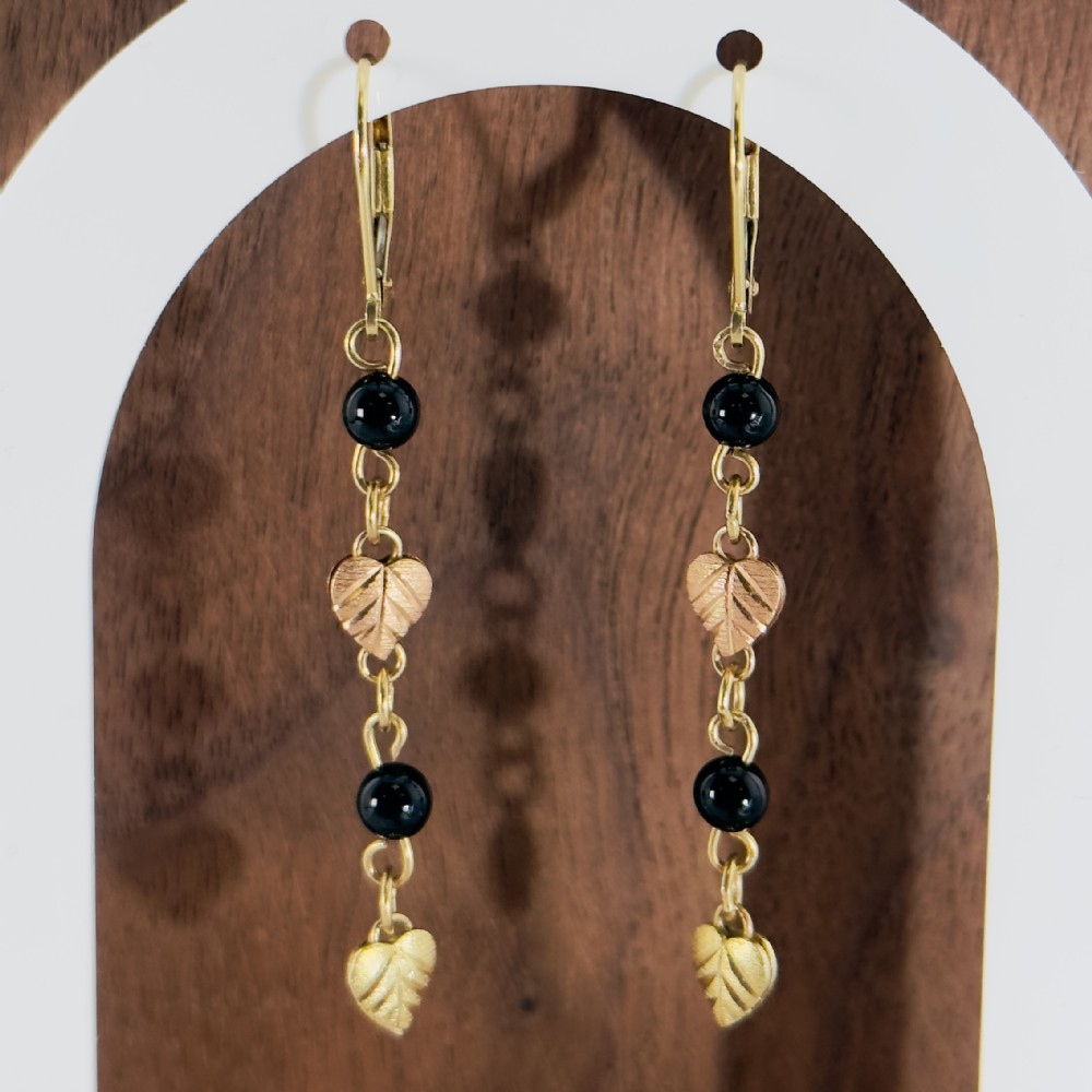 A pair of 14ct gold drop earrings featuring black onyx beads, textured leaf-shaped motifs, and hinged leverback closures.