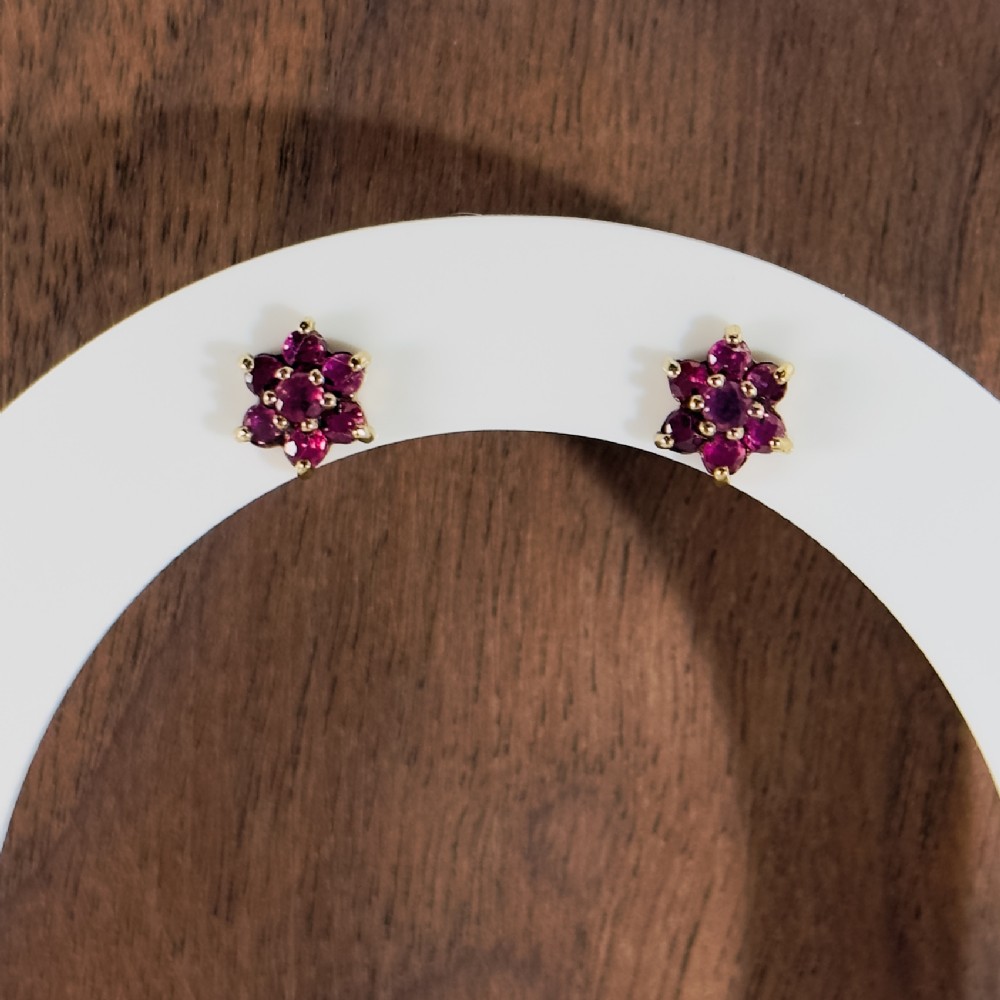 A pair of 9ct yellow gold flower-shaped cluster stud earrings set with seven round facetted purple amethyst gemstones in claw settings.