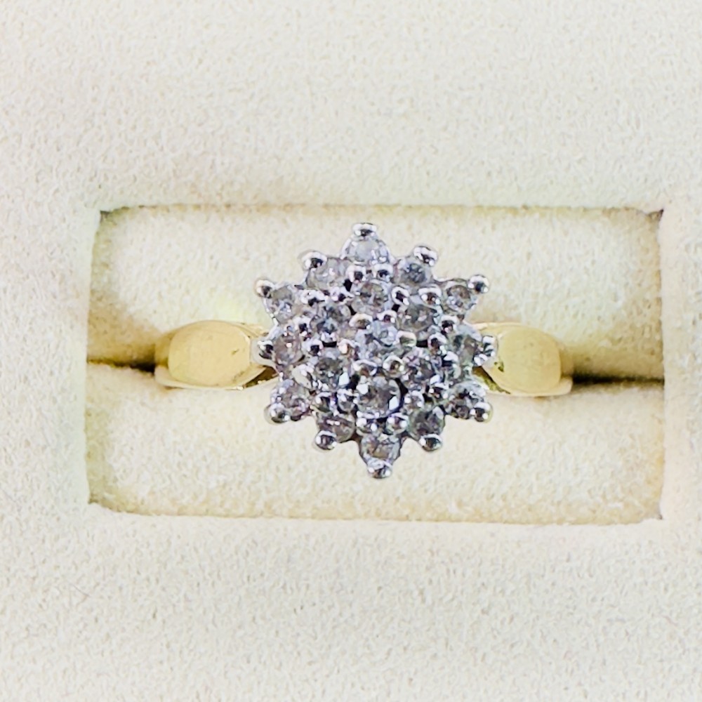 An 18ct yellow gold cluster ring set with round diamonds in a starburst pattern on a plain polished band.