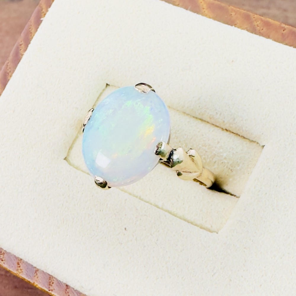 An antique 9ct gold solitaire ring set with a single large oval cabochon opal held by claw settings.