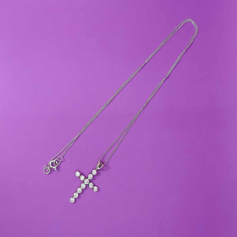 A 9ct white gold cross pendant composed of round bezel-set diamonds attached to a delicate chain. View X